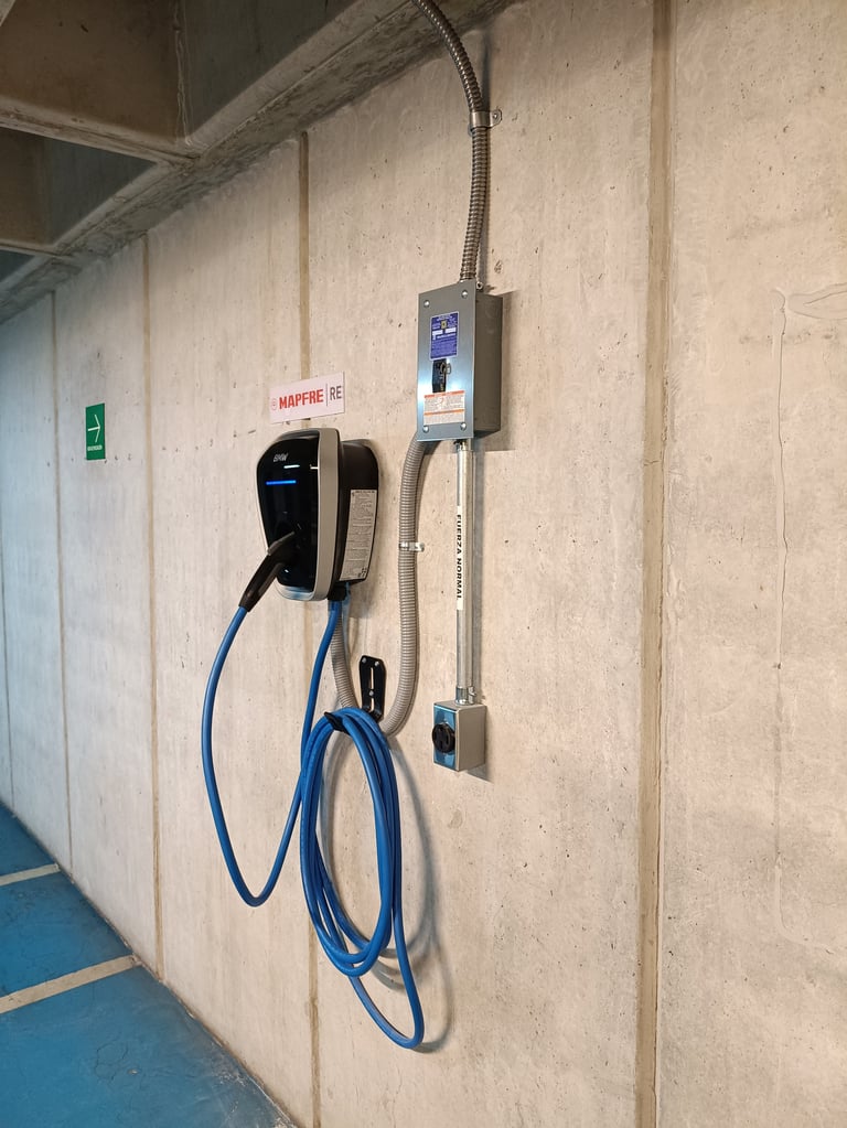 Electric vehicle charging station mounted on a concrete wall with blue charging cable coiled below