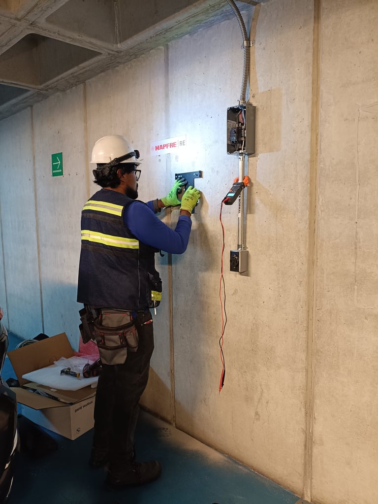 Técnico certificado por CONOCER con casco y chaleco de seguridad instalando cableado eléctrico y contactos en muro de concreto