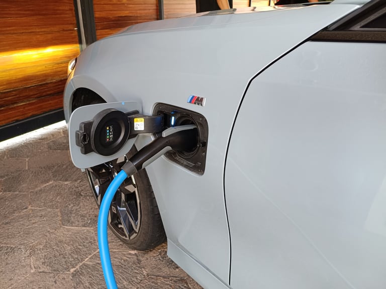 Auto eléctrico blanco cargando con cable azul conectado al puerto de carga